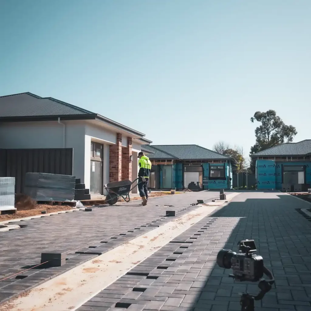 Tradesman carrying a wheelbarrow full of pavers on a job site