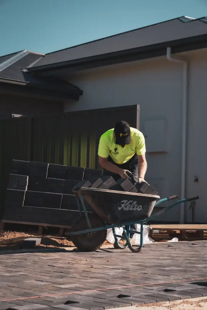 Tradesman employee putting pavers into a wheelbarrow