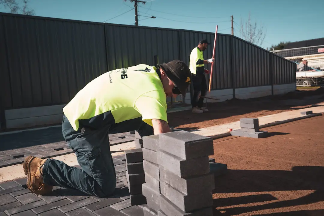 Tradesman laying paving bricks on a levelled dirt surface